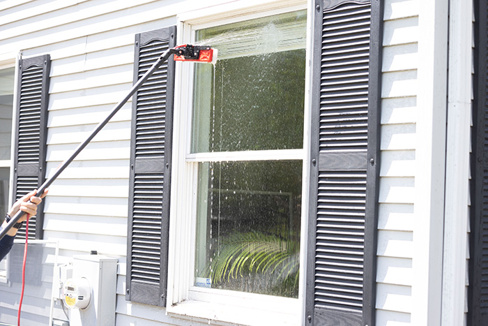 professional with window cleaning brush cleaning window on white home
